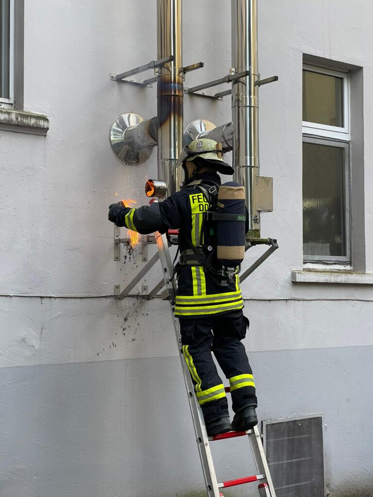 Ein Feuerwehrmann öffnet den Kamin an einer Revisonsöffnung, Foto: Feuerwehr Dortmund
